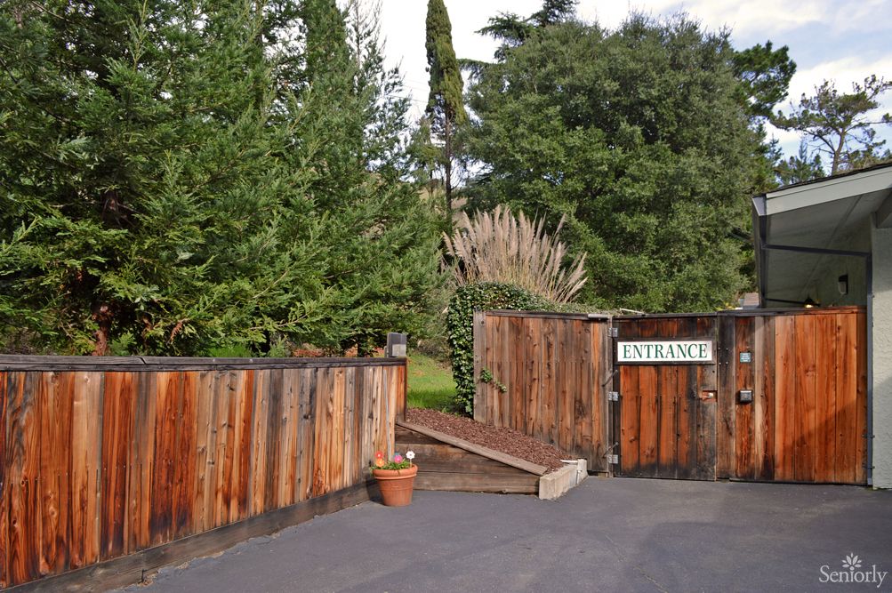 A wooden gate with an 'Entrance' sign, surrounded by trees.