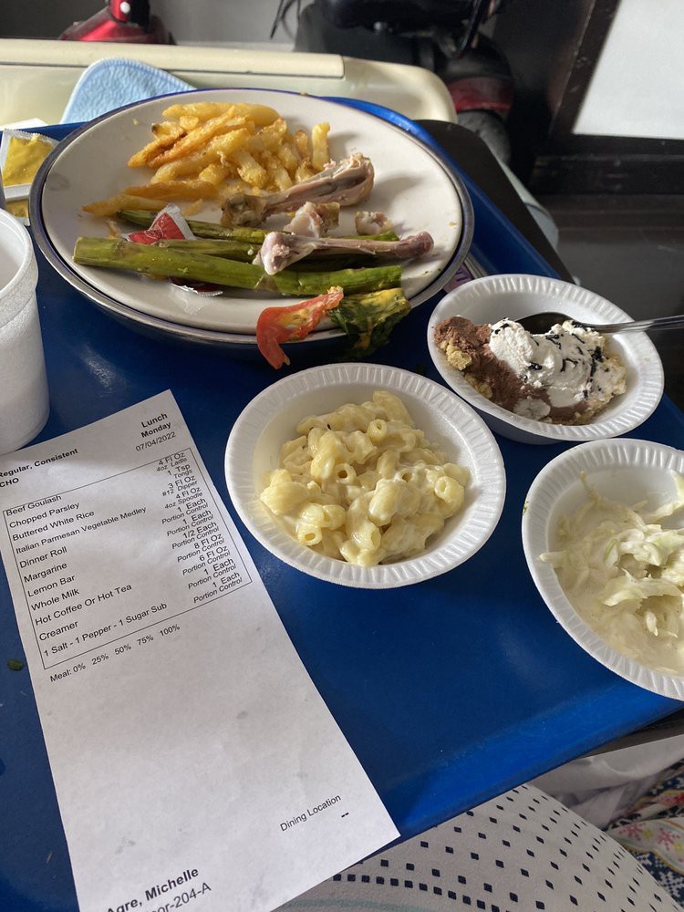 A meal served on a blue tray featuring fries, asparagus, chicken, and various side dishes.