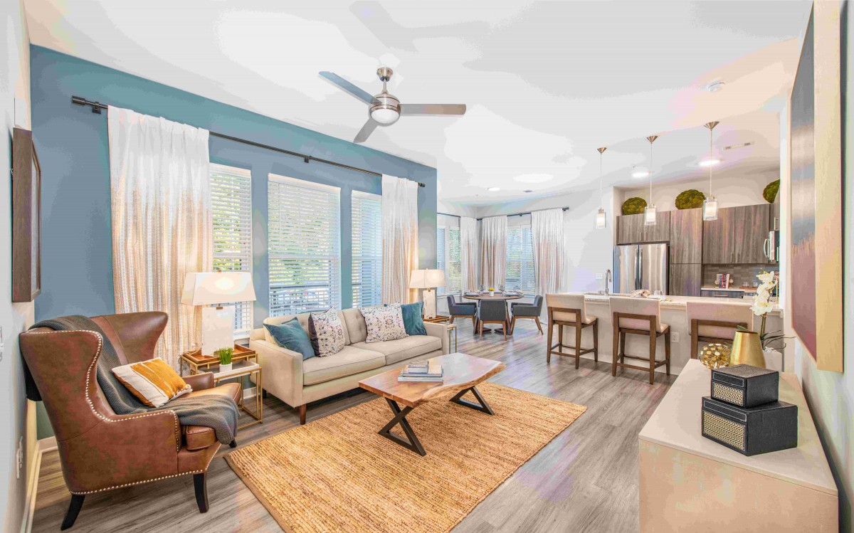 A modern open-floor living area featuring a cozy sofa, stylish coffee table, and a kitchen with a large island and bar stools.