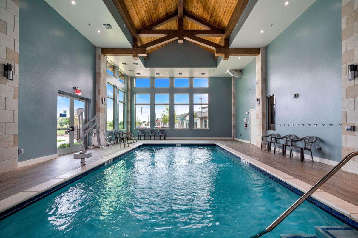 A spacious indoor swimming pool with high ceilings and large windows letting in natural light.