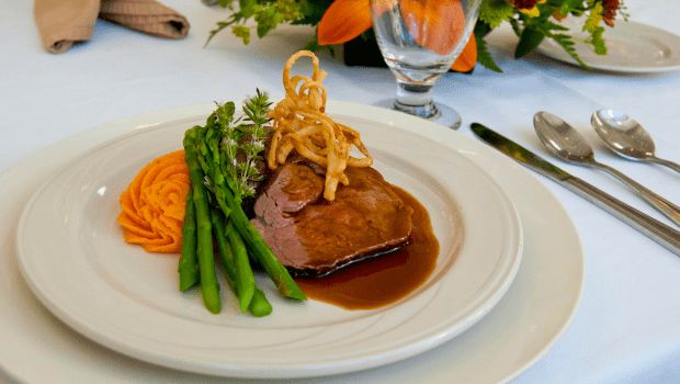 A gourmet steak dinner with asparagus and mashed potatoes, topped with crispy onion rings.