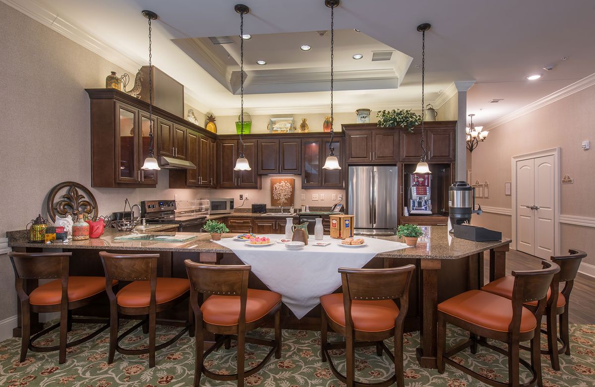 A modern kitchen with wood cabinets, stainless steel appliances, and an island counter with pendant lighting.