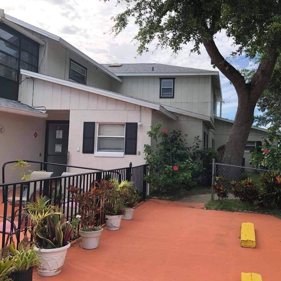 A residential house with a parking area and potted plants.