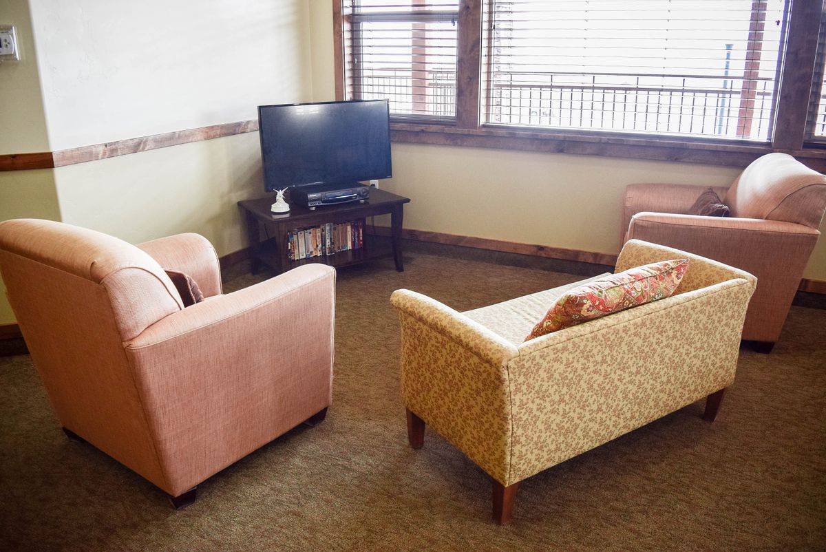 A cozy living room with a sofa, armchair, and a TV near a window.