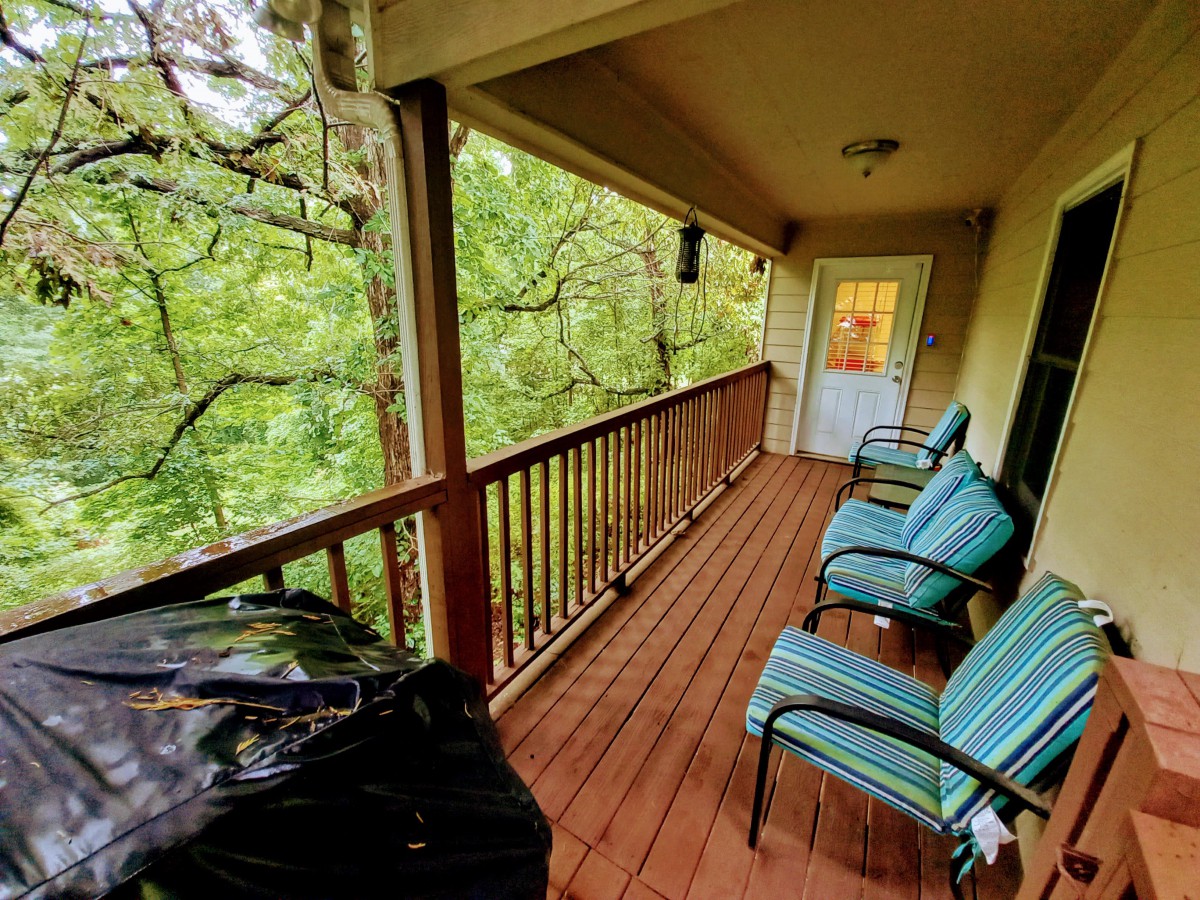 A cozy balcony with seating overlooking a lush forest.