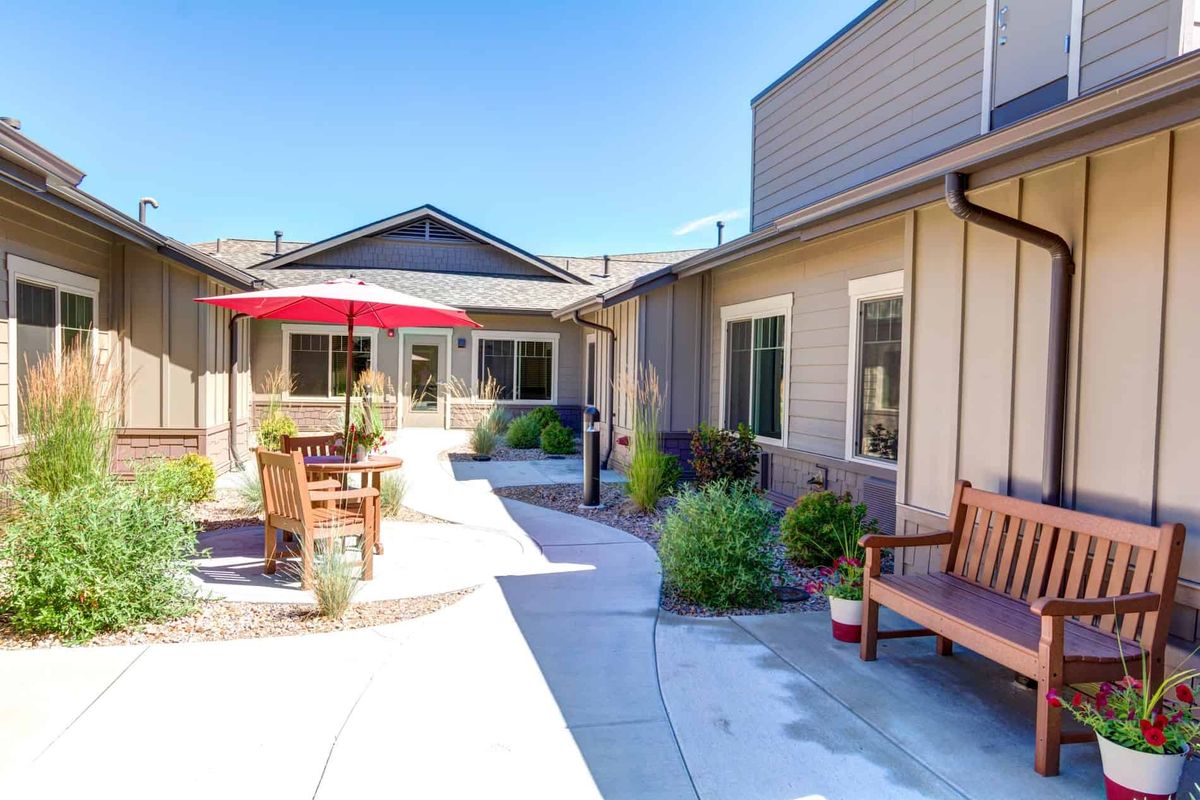 A bright courtyard with seating areas and potted plants under a clear blue sky.