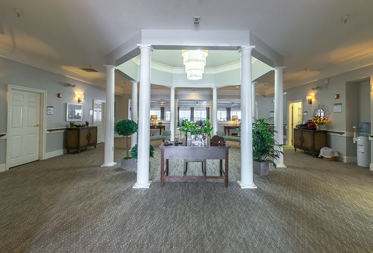 A spacious lobby with white columns, plants, and elegant decor.