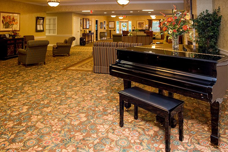 A grand piano in a cozy hotel lobby with comfortable seating and elegant decor.
