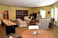 A cozy living room with a variety of furniture including sofas, chairs, a table, and a bookshelf, all set on hardwood flooring.