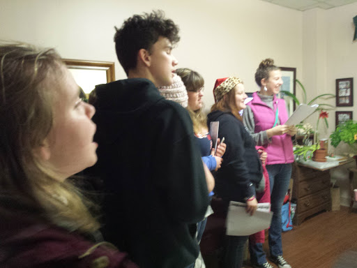 A group of young individuals engaged in an indoor activity, possibly singing or performing.