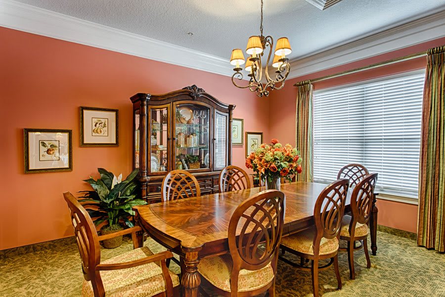 A warm and elegant dining room with a wooden table, chairs, and a chandelier.