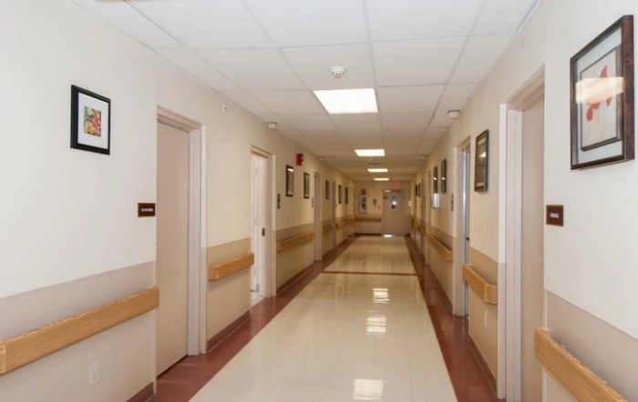 An empty hospital corridor with clean floors and closed doors.