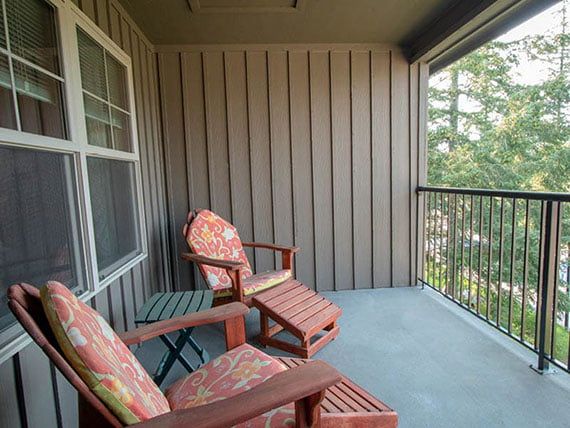 Two wooden chairs with cushions on a cozy balcony.