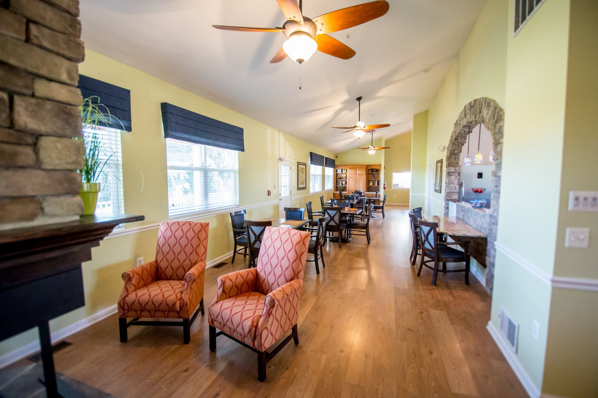 A spacious living room with comfortable seating, ceiling fans, and large windows.