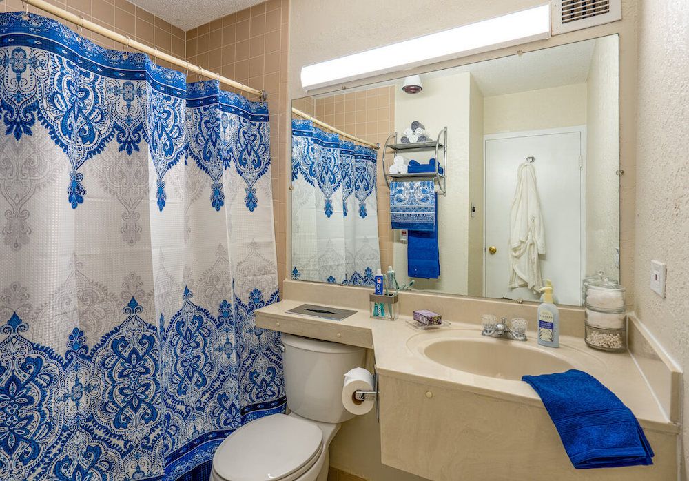 A bathroom featuring a blue and white shower curtain with matching towels.