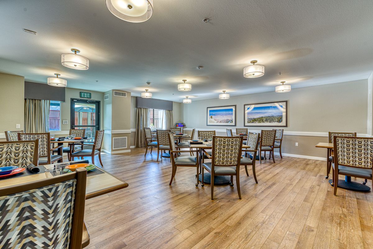 A cozy dining area with tables and chairs arranged neatly on a wooden floor.