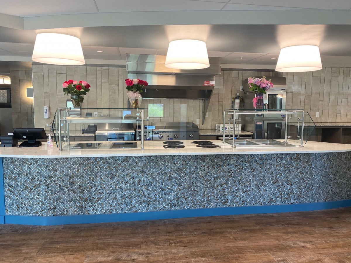 An empty modern cafeteria counter with stylish lighting and floral decorations.