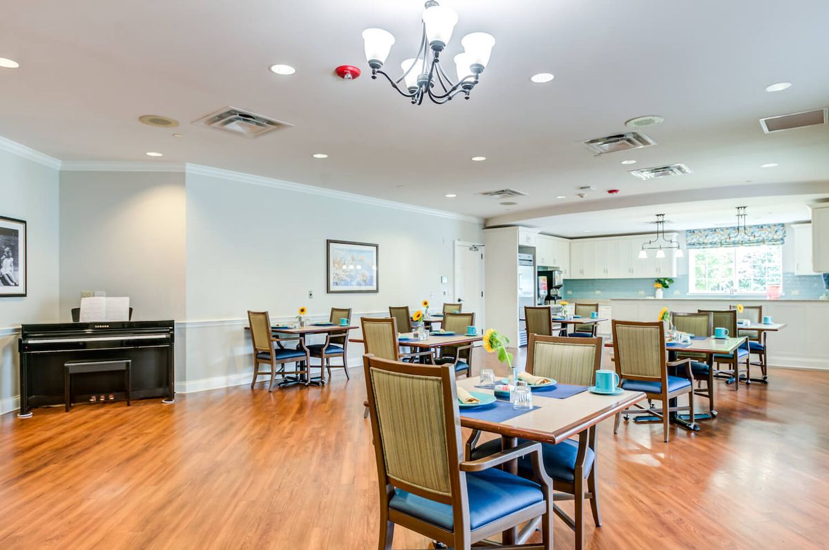 A well-organized dining area with neatly arranged tables and chairs, featuring a chandelier and wooden flooring.
