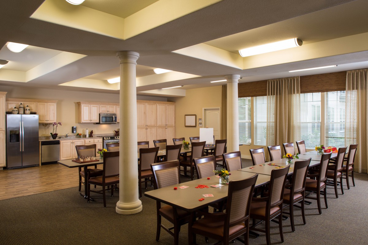 An organized meeting room with tables and chairs alongside a small kitchen area.