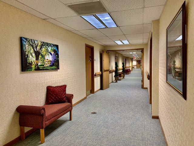 A long office corridor with doors on either side and artwork on the walls.