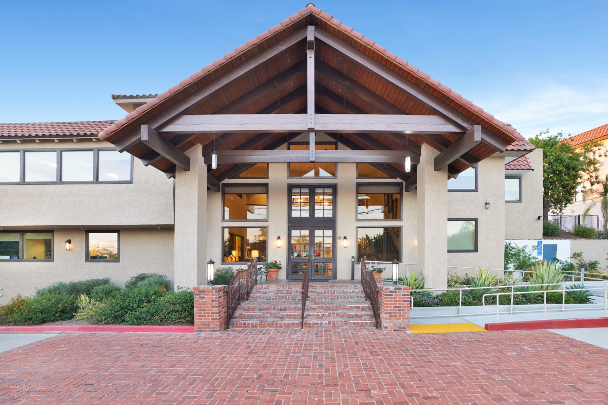 A modern building entrance with brick stairs and a peaked roof.