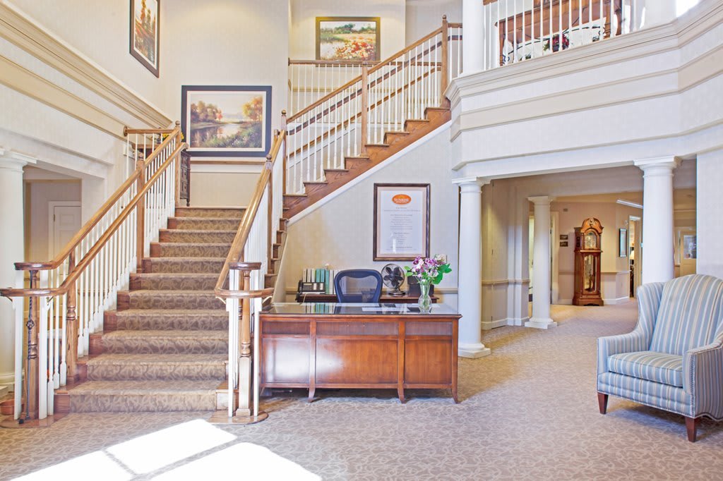 A well-lit lobby featuring a grand staircase and a reception desk.