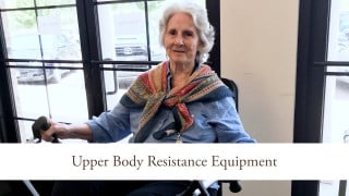 An elderly woman using upper body resistance equipment in a wheelchair.
