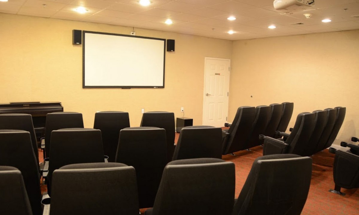 A cozy home theater with upholstered seating facing a large projection screen.