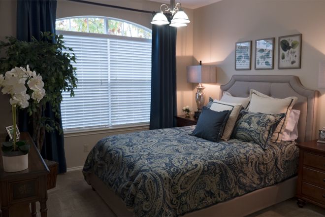 A cozy bedroom with a neatly made bed, large window, and elegant decor.