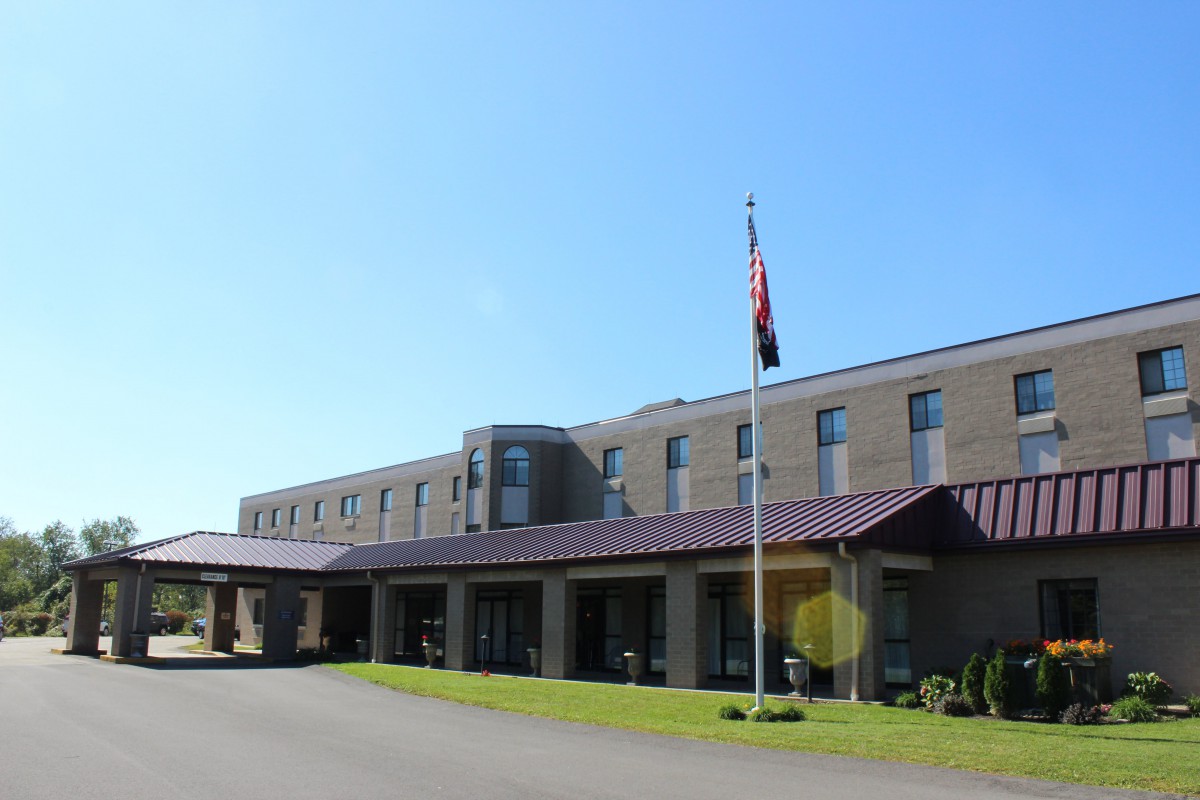 A building with a flagpole against a clear blue sky, surrounded by grass.