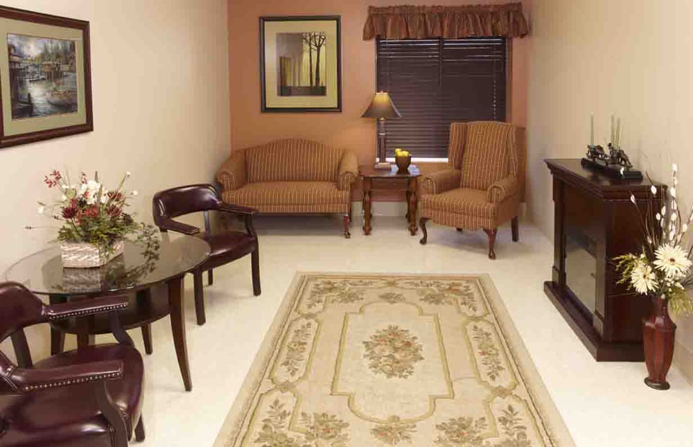 A cozy living room with a sofa, chairs, table, and a patterned rug.