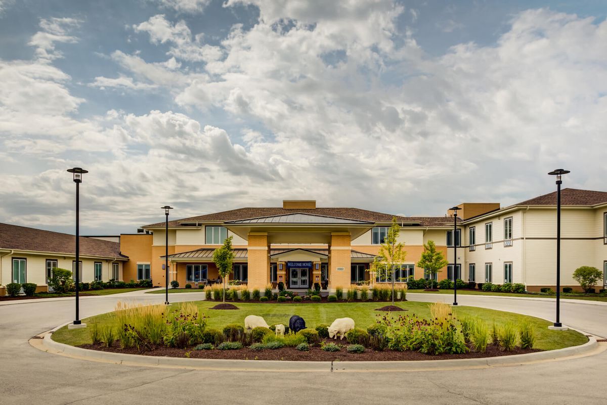 A modern building with a landscaped entrance and cloudy sky overhead.