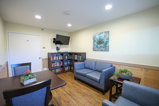 A cozy and inviting lounge area featuring comfortable seating, a bookshelf, and a television.