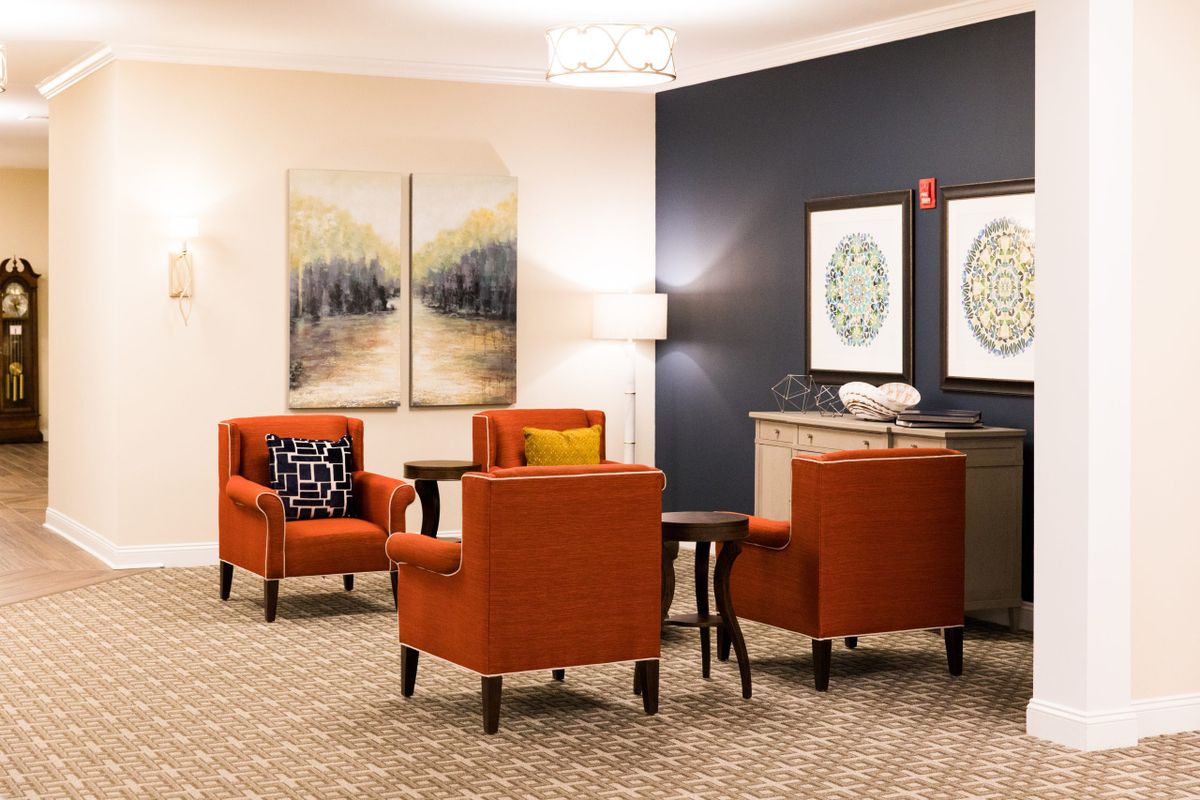 A modern lounge area with orange chairs and decorative artwork.