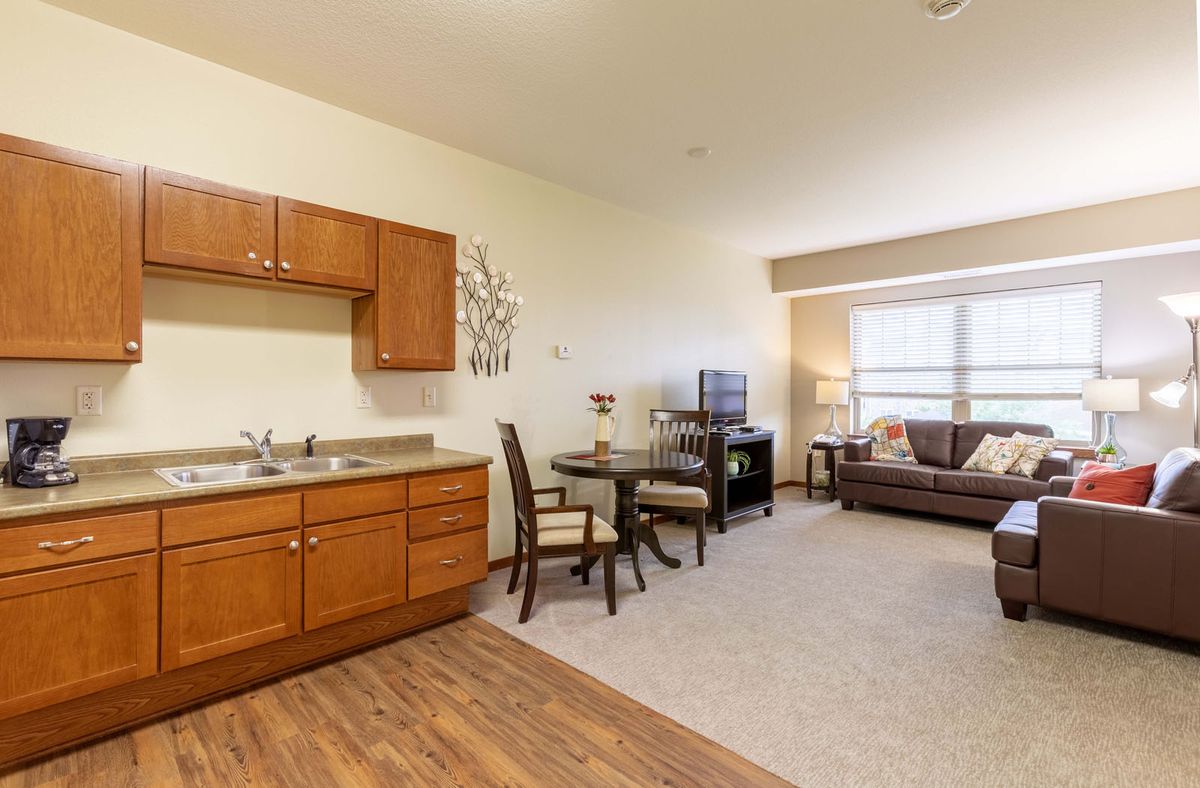 A cozy apartment with an open living room and kitchenette, featuring dining furniture and a comfortable seating area.