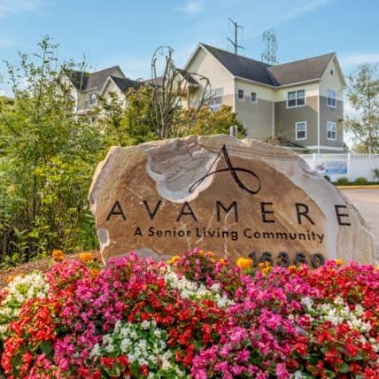 Entrance sign for Avamere Senior Living Community surrounded by colorful flowers.