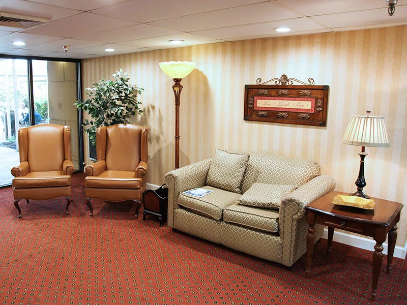 A cozy waiting room with a sofa, armchairs, and warm lighting.