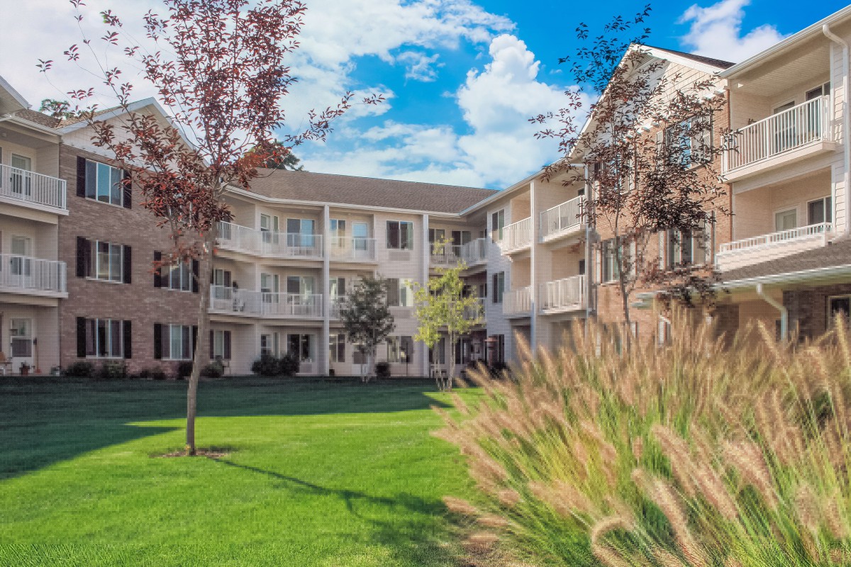 A residential apartment building with balconies and a well-maintained lawn.