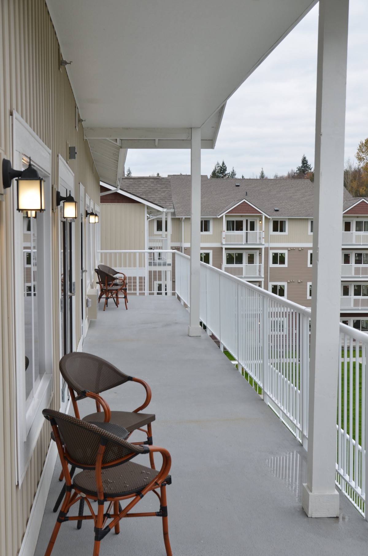 A balcony with outdoor chairs overlooking an apartment complex.