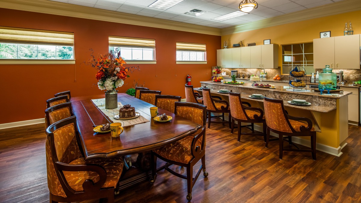 A cozy dining area with a wooden table and chairs, adjacent to a kitchen with modern cabinetry.