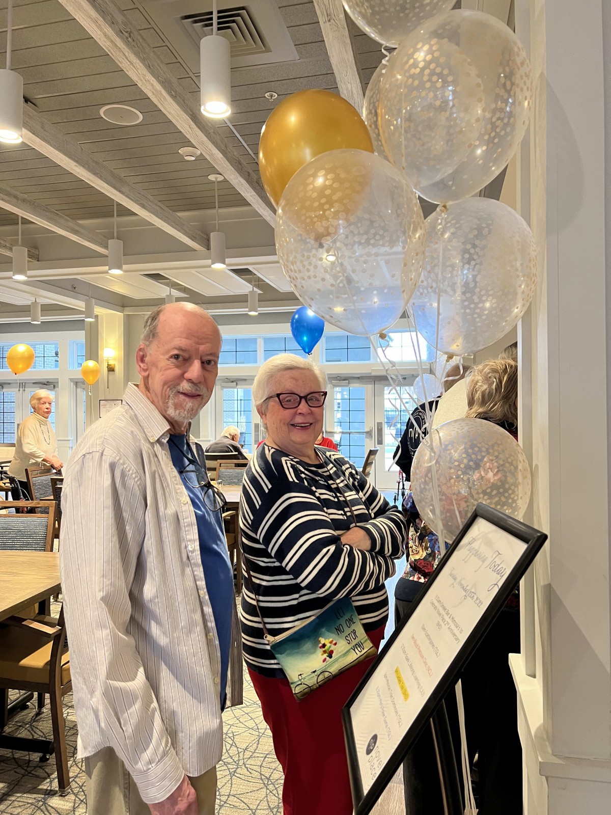 Two people standing in a restaurant with decorative balloons.