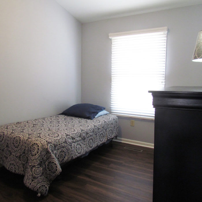 A minimalist bedroom with a single bed and dresser.