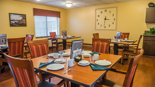 A cozy dining area set up for a meal, featuring wooden tables and chairs, complete with place settings and decorative elements.