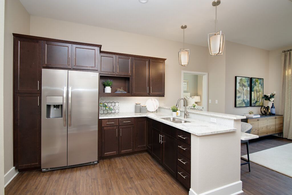 A modern kitchen with dark cabinets and stainless steel appliances.