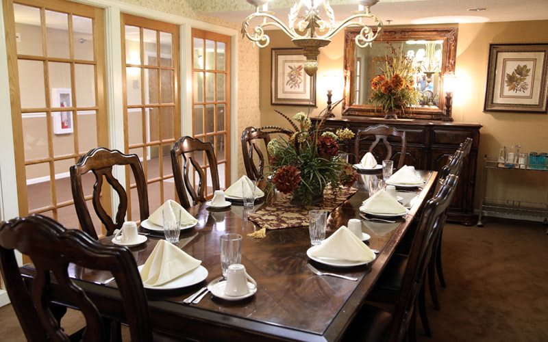 An elegantly set dining table with white napkins and decorative centerpiece in a well-decorated dining room.