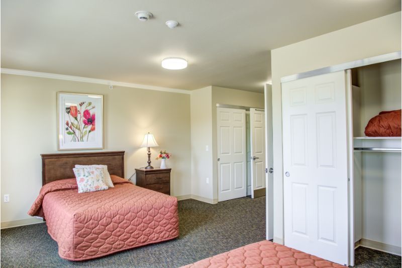 A cozy bedroom with two neatly arranged beds and a lamp on the nightstand.