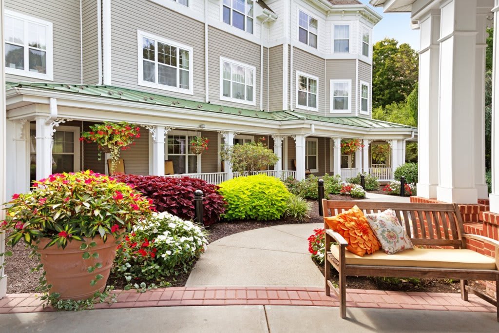 Beautifully landscaped garden area with a bench in front of a residential building.