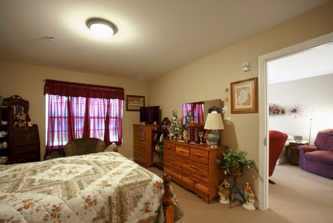 A cozy bedroom with a bed, dresser, television, and patterned curtains.