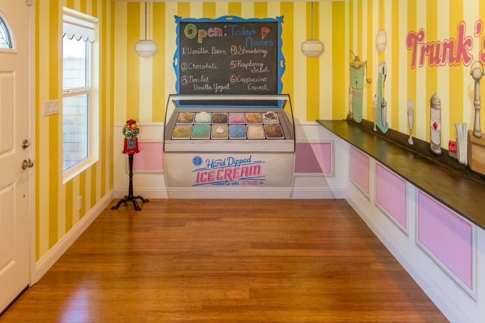 A colorful ice cream shop interior with a menu board and display case.