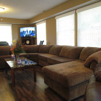 A cozy living room with a large brown sectional sofa, a coffee table, and a television.